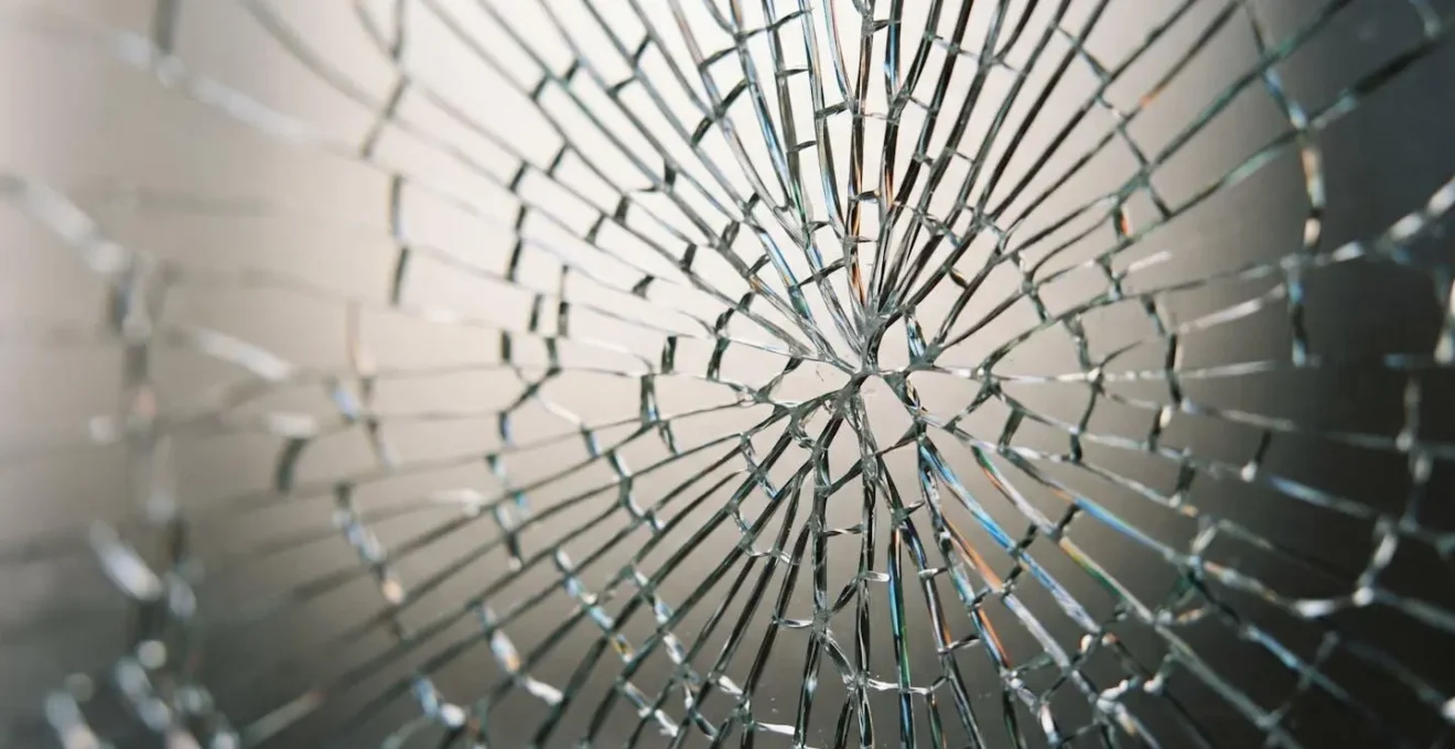 Gros plan détaillé sur une fissure dans du verre montrant la propagation d'un impact